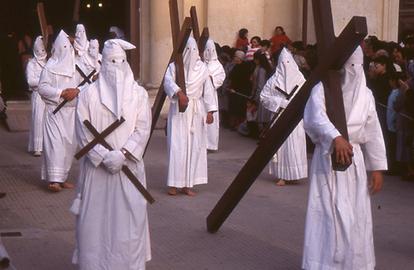 Hooded repenters pull or carry crosses.
